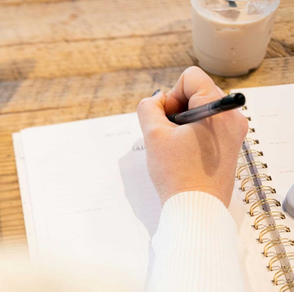zoom sur une main écrivant au stylo des démarches administratives