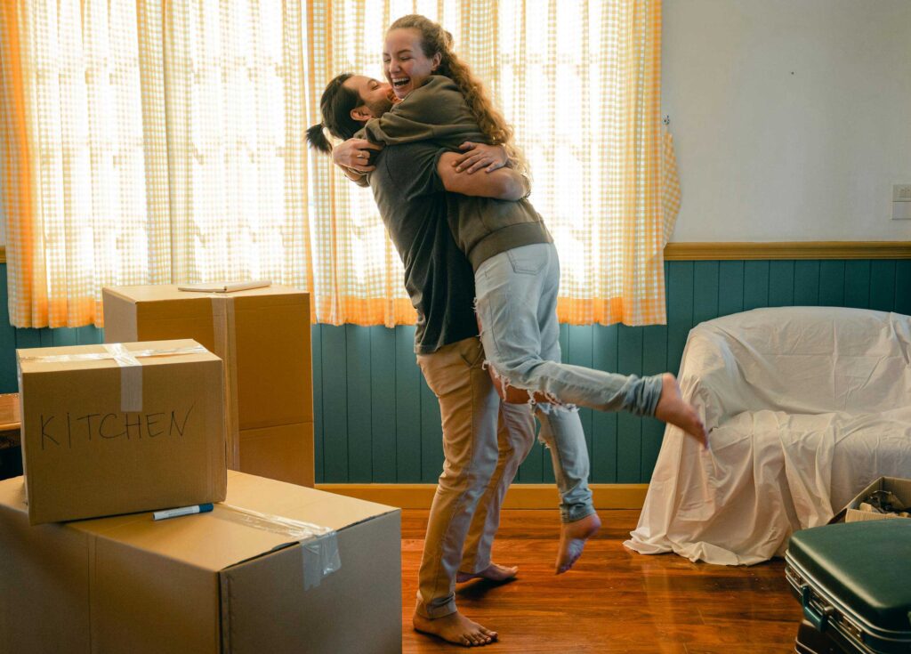 un couple se serrant dans les bras après avoir emménagé dans leur premier logement