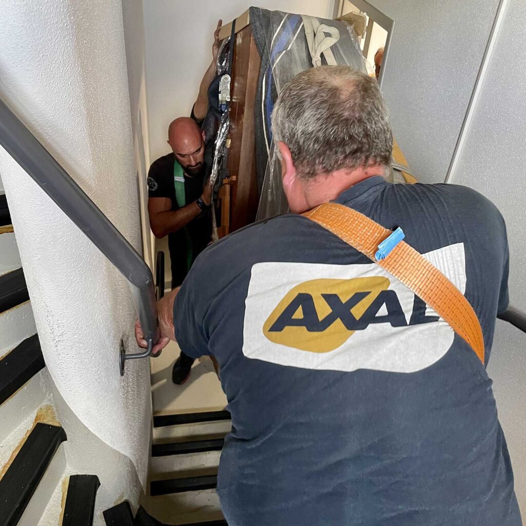 Techniciens Axal transportant un objet lourd dans une cage d'escalier étroite
