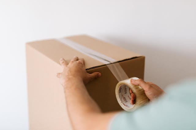 une personne scotchant un carton de déménagement